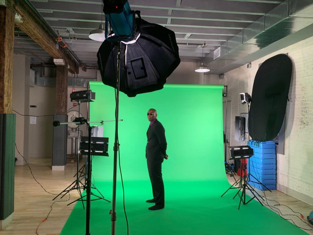 A man in suit filming in front of green screen
