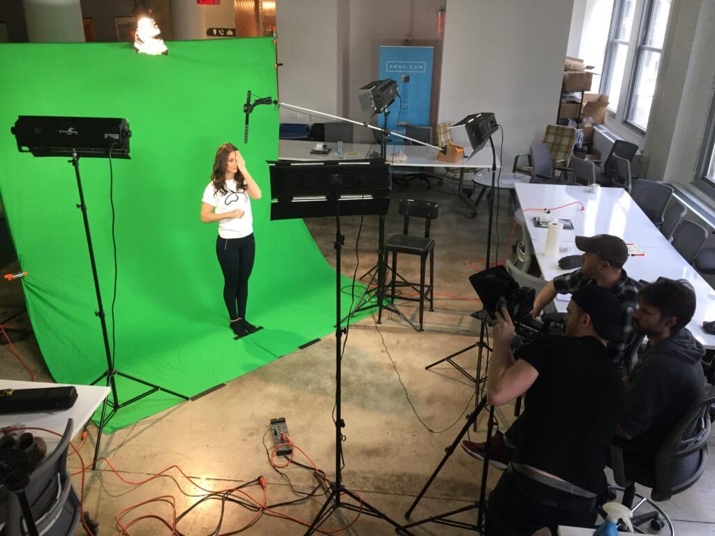 A woman being filmed in front of green screen for video marketing